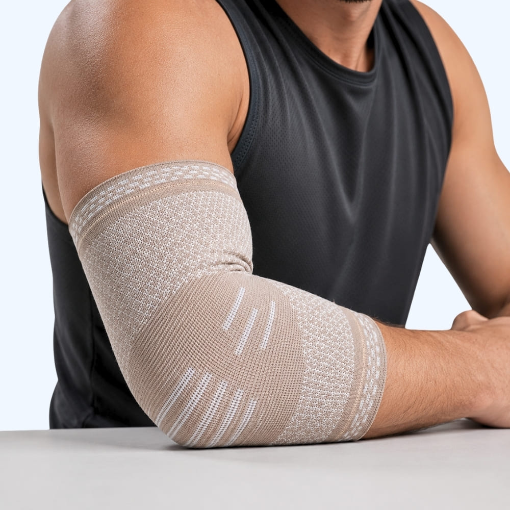 Person wearing a beige elbow support on a plain background