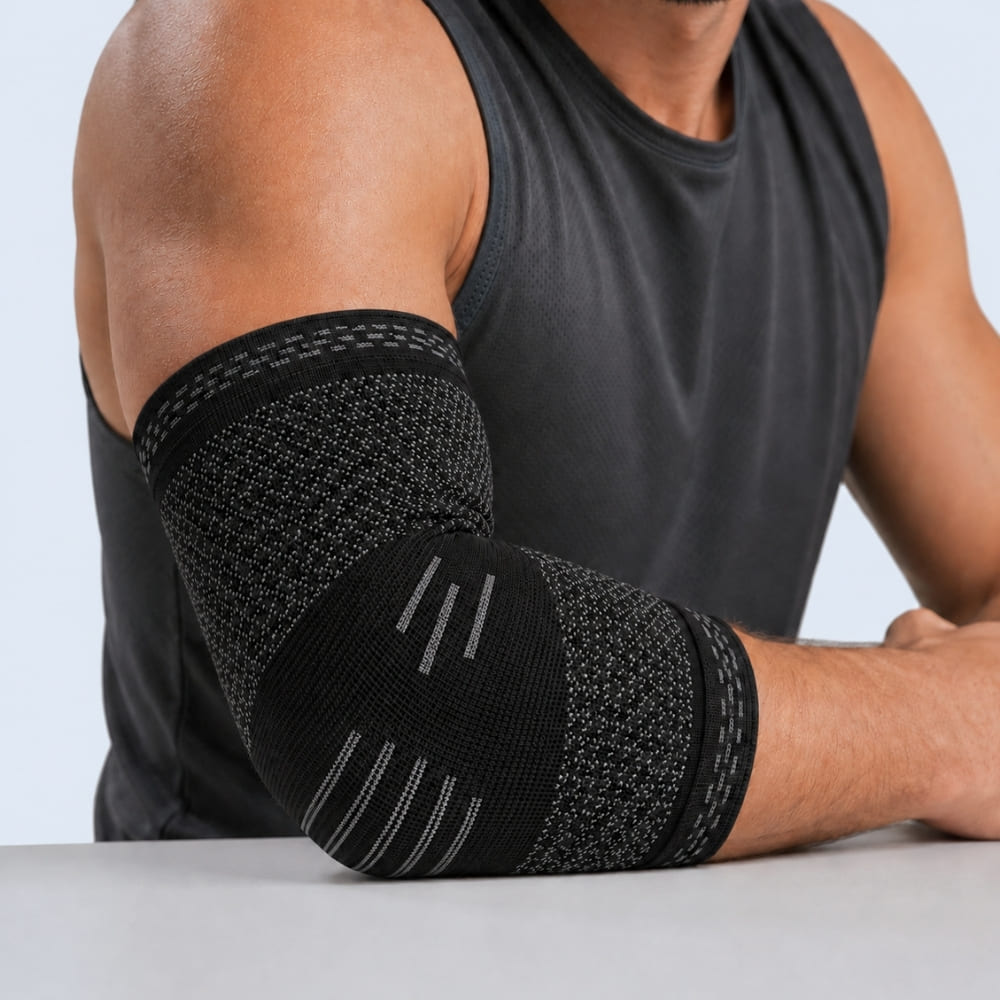 Person wearing a black elbow brace on a plain background