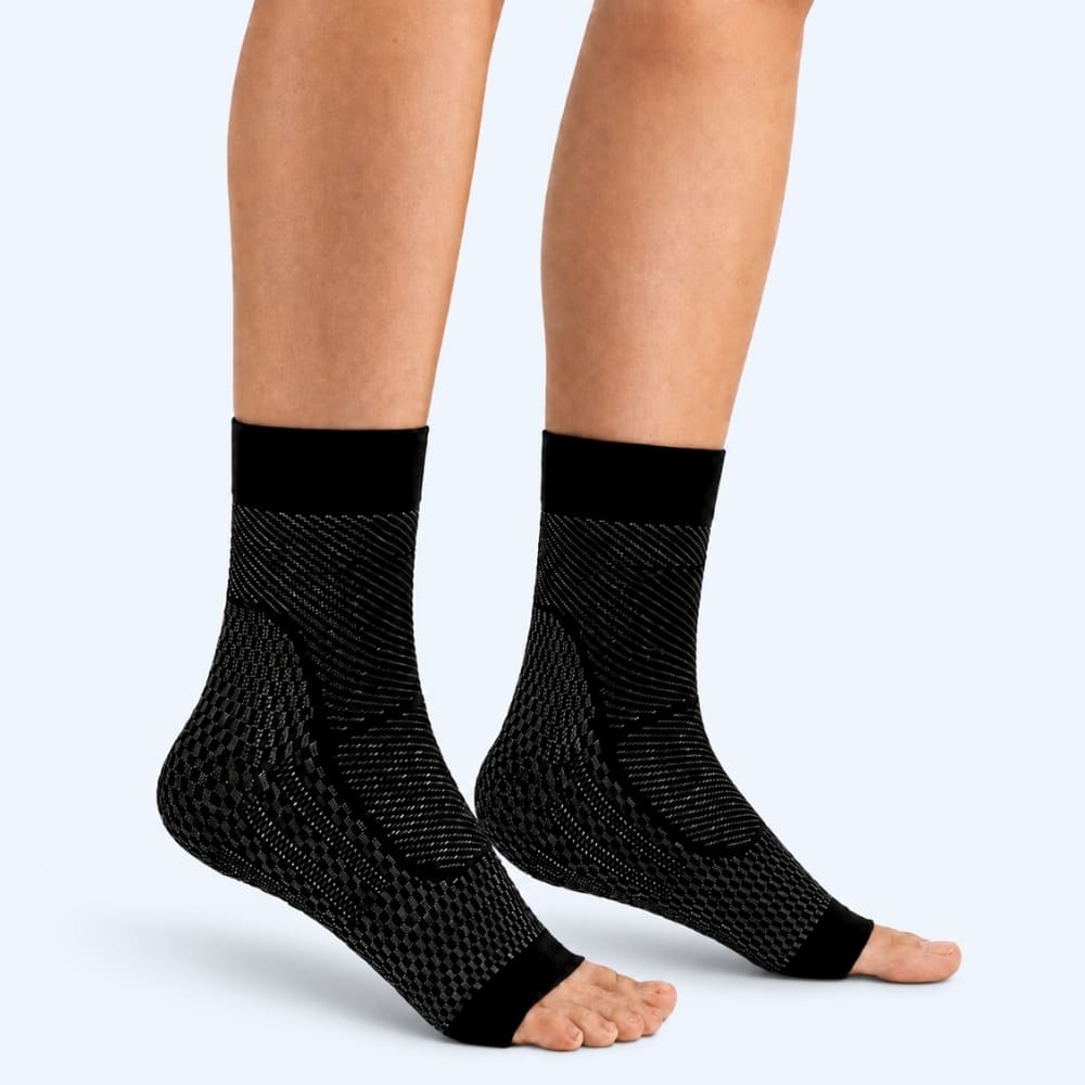 Black compression socks worn by a person on a light gray background