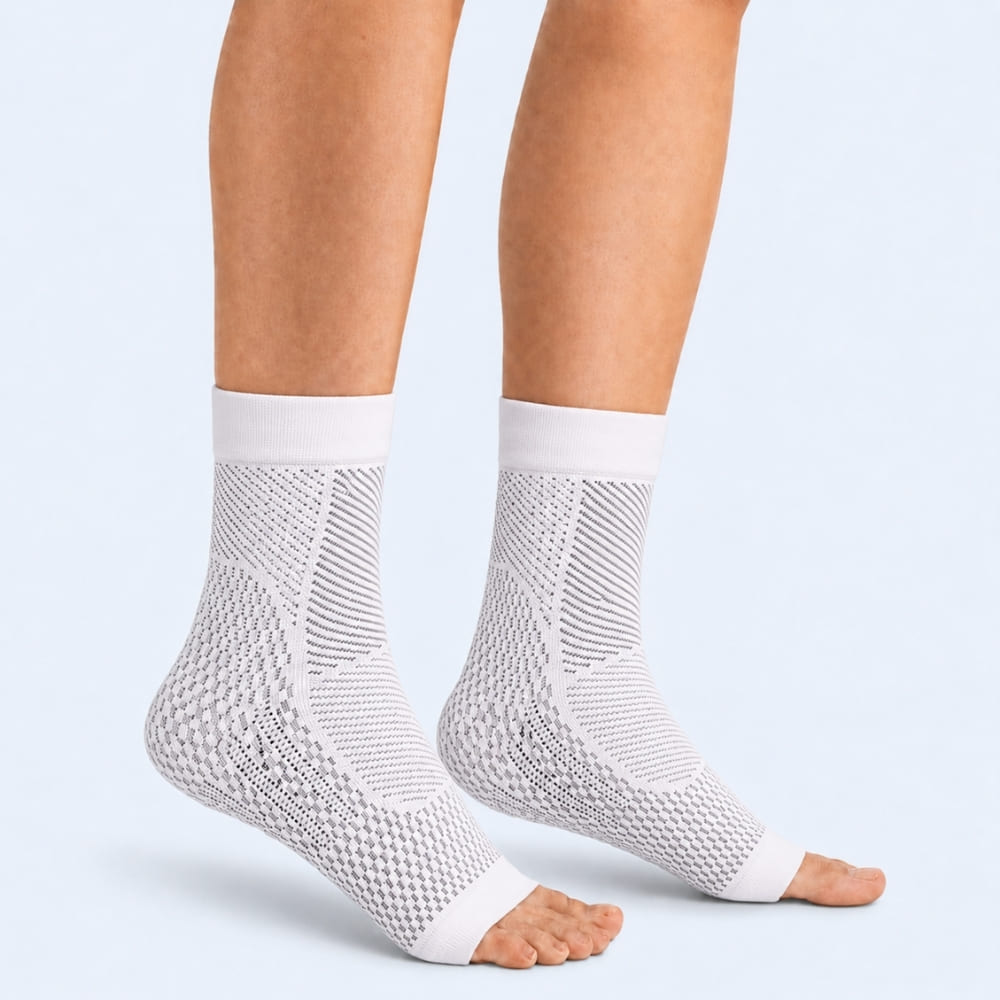 White compression foot sleeves for plantar fasciitis worn by a person on a light gray background