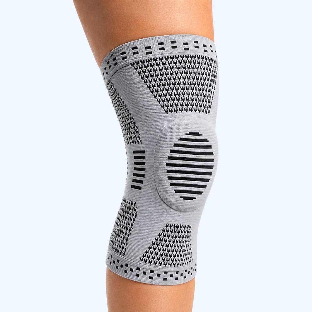 Gray knee brace on a person's knee against a white background